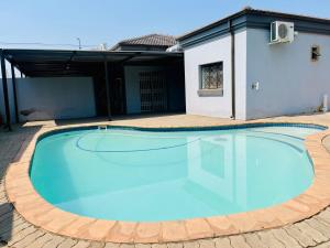 a large swimming pool in a yard with a house at Genza Guesthouse in Pretoria in Pretoria