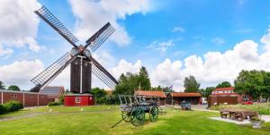a windmill in a field with a picnic table and benches at Kleine Austernperle in Dornumersiel