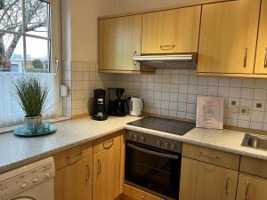 a kitchen with wooden cabinets and a stove top oven at Ferienhaus Leuchtqualle in Dornumersiel +25 photos