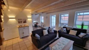 a living room with two couches and a kitchen at Ferienhaus Pfeffermuschel in Neßmersiel