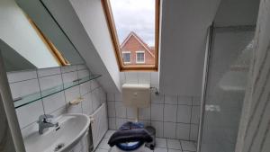 a small bathroom with a sink and a window at Ferienhaus Pfeffermuschel in Neßmersiel +22 photos