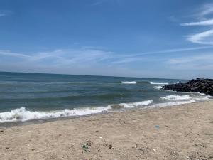 a sandy beach with waves in the ocean at BlueWaves in Pondicherry