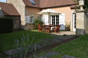 een tafel en stoelen met een parasol in de tuin bij Charmante maison avec jardin et air conditionné au coeur d'un village historique ! in Verneuil-en-Bourbonnais +3 foto's