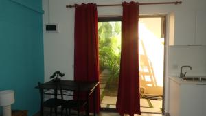 a room with a red curtain and a table and a window at Studio le Dauphiln du Lagon Bleu - Grand Baie in Grand Baie