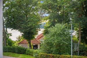 a house in the midst of trees and bushes at MAISUITES Sperling - Zentrale Ferienwohnung mit Boxspringbett, Kaffeevollautomat, WLAN & seitlichem Seeblick in Mölln +25 photos