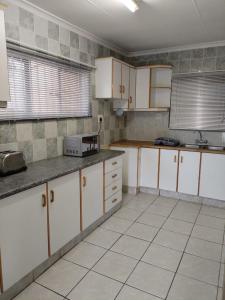 a kitchen with white cabinets and a tile floor at La' Romi Self Catering Units in Pietermaritzburg