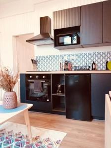 a kitchen with a black refrigerator and a stove at Little Corsaire Gare parking & bus in Saint Malo