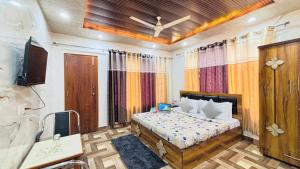 a bedroom with a bed and a tv and curtains at The Moonlight Stay Kasauli in Kasauli