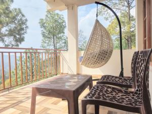a porch with two chairs and a table and a hanging lamp at The Moonlight Stay Kasauli in Kasauli