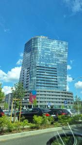 a tall glass building with cars parked in front of it at Apartament Hanza Tower 13th floor with balcony in Szczecin