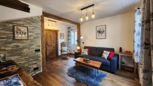 a living room with a blue couch and a brick wall at chalet cosy, jacuzzi privé, calme, idéal moto rando vélo in Bellecombe