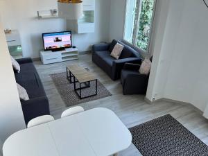 a living room with a couch and a tv at Maison Mont Valérien Spacious Family and Business Stay with AC and Parking, near Paris La Défense in Nanterre
