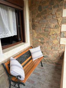 a bench with two pillows sitting in front of a window at The Garden House, Sitia in Sitia