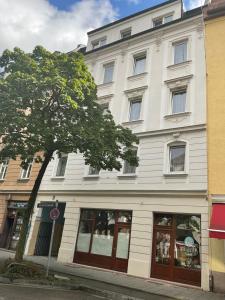 Un edificio blanco con un árbol delante. en Pension&Hostel Anna - Monteurzimmer, en Múnich
