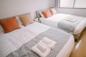 two beds and a couch in a room at リトリートコート薬院 in Fukuoka