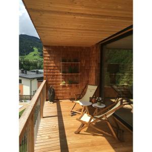 a wooden deck with chairs and a table on it at ALMMONTE LIGNUM Lodge in Wagrain