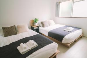 a bedroom with two beds with towels on them at リトリートコート薬院 in Fukuoka