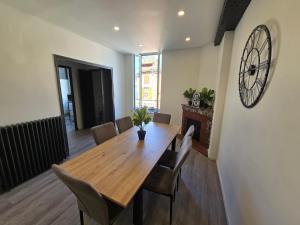 a dining room table with chairs and a clock on the wall at Spacieux 120 m2 en 3 chambres centre Foix - 2 sdb et 2 wc - Parking gratuit à 1 Minute in Foix