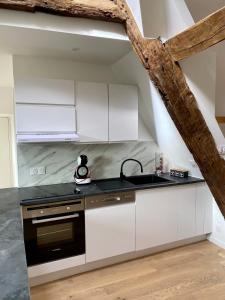 a kitchen with white cabinets and a black stove at Les toits de Paimpol in Paimpol