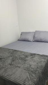 ein Bett in einem weißen Zimmer mit einer Decke darauf in der Unterkunft Lar Aconchego 2 in Palmas