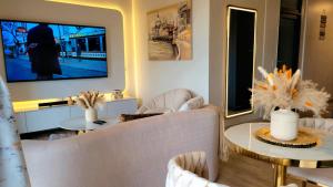 a living room with white chairs and a television at Luxury, Comfort and Unforgettable View of Sandton in Johannesburg
