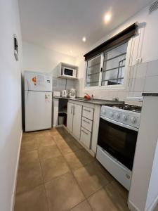 a kitchen with white appliances and white cabinets at Granville in Valeria del Mar