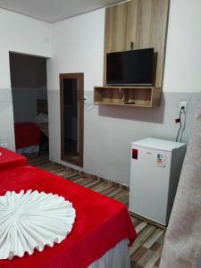 a room with a refrigerator and a tv on the wall at Pousada Massayó in Maceió