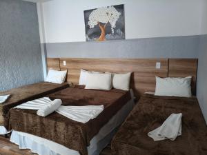 a bedroom with two beds with white pillows at Pousada Massayó in Maceió