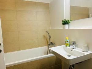 a bathroom with a white sink and a bath tub at Stylish 19th-Floor Klingerka Apartment with Stunning Castle Views & Free Parking in Bratislava +3 photos