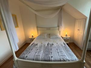 1 Schlafzimmer mit einem Himmelbett und 2 Tischen in der Unterkunft Cottage avec terrasse Domaine golf de Limère prox Orléans in Ardon + 15 Fotos