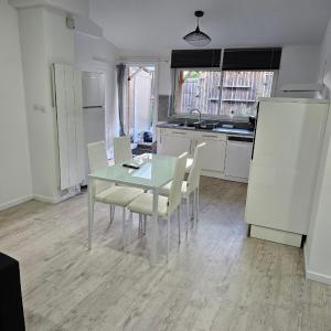 a kitchen with a glass table and white chairs at Appartement centre hourtin in Hourtin