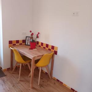a wooden table with yellow chairs and a plant on it at La maisonnette du Chambon in Monistrol-sur-Loire