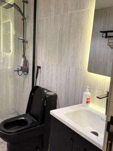 ein Badezimmer mit einer schwarzen Toilette und einem Waschbecken in der Unterkunft شقة الراحة in Tabuk