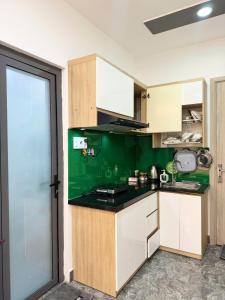cocina con paredes verdes y armarios blancos en Four P Home Phu Nhuan, en Ho Chi Minh