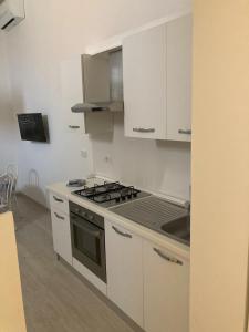 a kitchen with white cabinets and a stove top oven at Villetta con giardino di fronte al mare in Principina a Mare