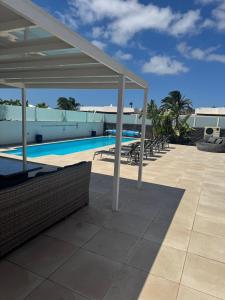- une vue sur la piscine et un pavillon dans l'établissement Villa Ashdene - luxury modern villa with large heated pool wifi uk tv bar & BBQ, à Playa Blanca