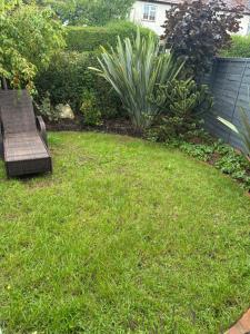 a yard with a bench in the grass at Studio apt with private parking in Teddington +2 photos