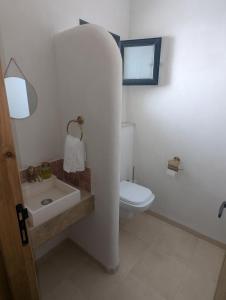 a bathroom with a white toilet and a sink at Magnifique villa typique avec piscine privée in El Guecheïne