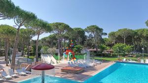a swimming pool with chairs and a playground at Campeggio del Forte in Marina di Bibbona