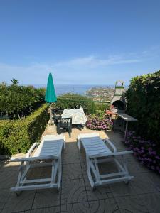two white chairs and a table and a green umbrella at Villa Rosi&Maria in Coccorino