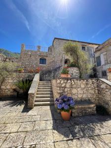 a stone building with stairs and flowers in front at Case Vacanza Baglio Ciambre in Borgetto