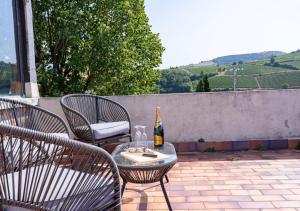 a table with a bottle of wine and chairs on a patio at Le Clos Poncétys - Villa avec Piscine in Davayé +51 photos
