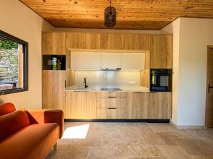 a kitchen with wooden cabinets and a couch at CAP PARADISU - Chalet vue mer et montagne in Santa-Maria-di-Lota
