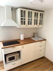 a kitchen with white cabinets and a sink and a microwave at White Sand Studio in Pāvilosta
