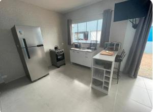 a kitchen with a refrigerator and a sink and a counter at Sobrado 02 com Terraço Panorâmico e Churrasqueira - 4 min a pe ate a Praia - Condomínio Sobre as Ondas in Guaratuba