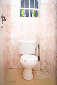 J and A Haven BnB- Langata Road opposite Uhuru gardens memorial park في نيروبي: مرحاض أبيض في حمام وورق جدران وردي