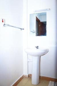 J and A Haven BnB- Langata Road opposite Uhuru gardens memorial park في نيروبي: بالوعة بيضاء في الحمام مع مرآة +17 صورة