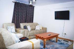 J and A Haven BnB- Langata Road opposite Uhuru gardens memorial park في نيروبي: غرفة معيشة مع أريكة وتلفزيون