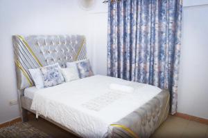 J and A Haven BnB- Langata Road opposite Uhuru gardens memorial park في نيروبي: غرفة نوم صغيرة بسرير مع ستارة
