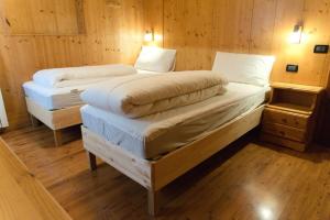 Habitación con 2 camas individuales y paredes de madera. en Dolomiti Garden Flat, en Villanova